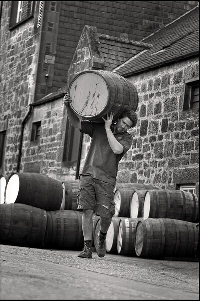 Een man draagt een Whisky vat